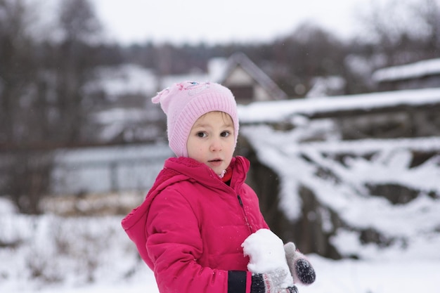 Een vijfjarig meisje kijkt verbaasd voor zich uit in de wintersneeuw rondom