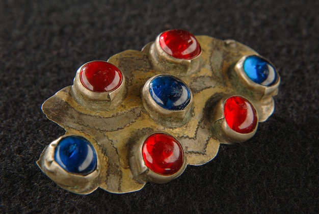 Een Vintage broche met kostbare rode en blauwe stenen geïsoleerd op een zwarte achtergrond Centraal-Aziatisch