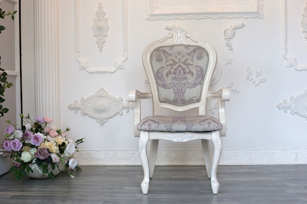 Foto een vintage zachte stoel staat tegen een witte muur. antiek wit houten stoel