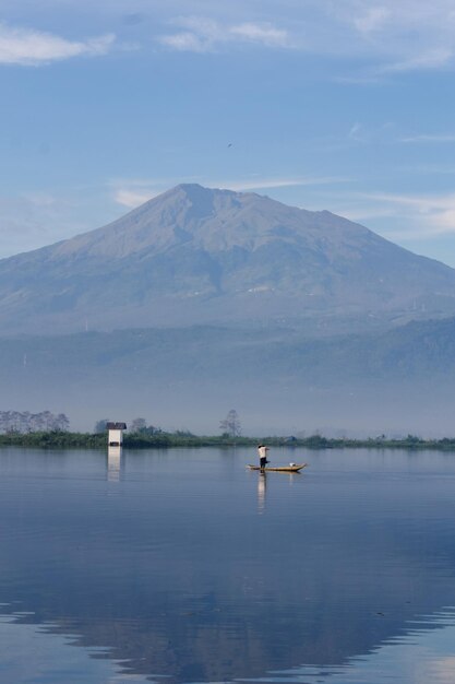 Een vissers vangen vis met houten kano in Rawa Pening met Mount Merbabu op de achtergrond Houten kano