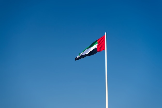 Een vlag van de Verenigde Arabische Emiraten die tegen een schone en rustige hemel vliegt. De VAE viert zijn nationale feestdag elk jaar op 2 december.