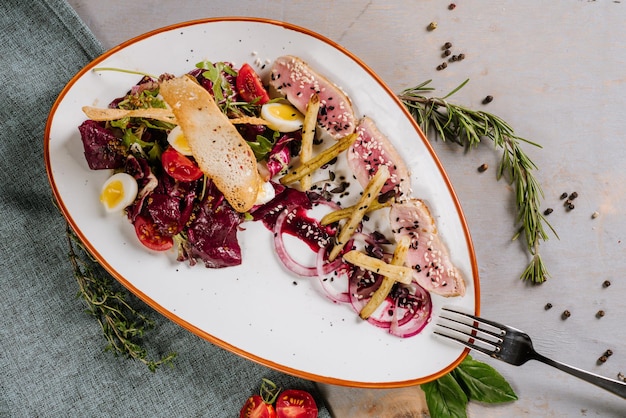 Een vleesgerecht met groenten, croutons en saus op de houten achtergrond