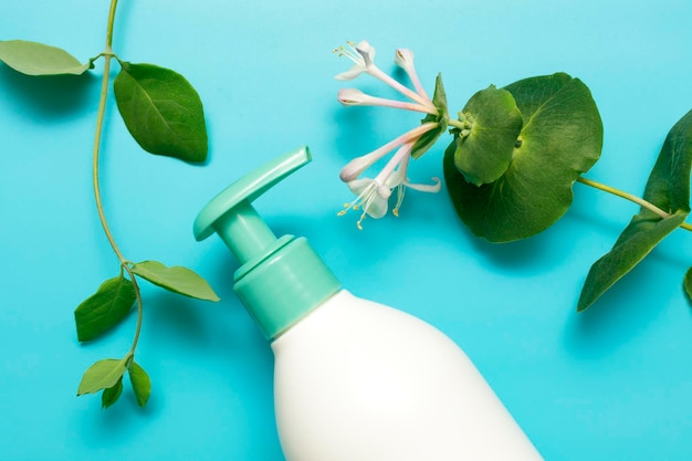 Een vloeibare handzeep met pomplotion uit de fles Huidverzorging voor een gezonde huid Natuurlijke cosmetica huidverzorgingsproduct crème lotion zeep op een blauwe achtergrond met groene bladeren en bloemen