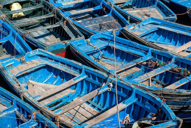 Een vloot blauwe vissersboten bij elkaar in de haven van Essaouira in Marokko