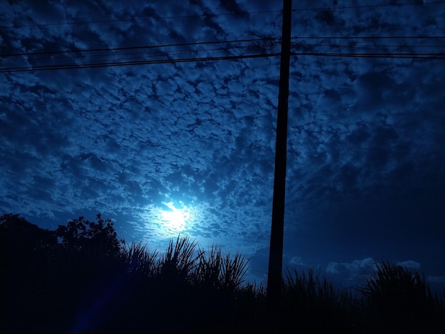 Foto een volle maan schijnt door een donkere nachtelijke hemel over een grasveld