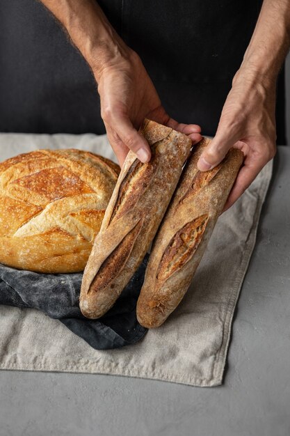 Een volwassen Europese mannelijke bakker houdt een rond vers brood in zijn handen een man in een bakkerij gistvrij