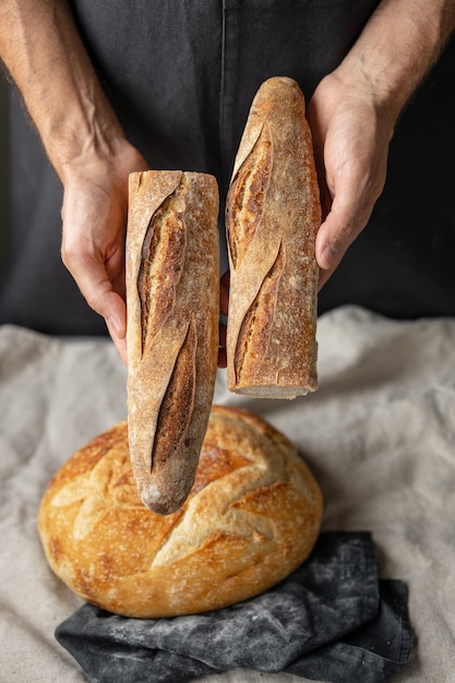 Een volwassen europese mannelijke bakker houdt een rond vers brood in zijn handen een man in een bakkerij houdt een