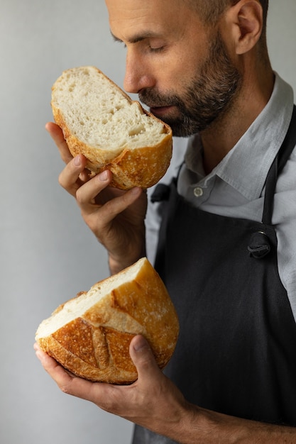Een volwassen Europese mannelijke bakker houdt een rond vers brood in zijn handen, een man in een bakkerij houdt