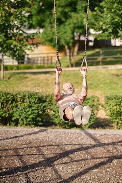 Een volwassen grijsharige man die traint in het park