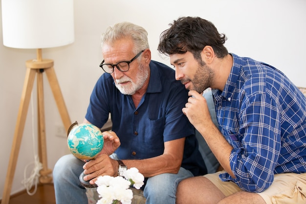 Een volwassen hipsterzoon en senior vader brengen samen tijd door thuis, praten, zorgen vader