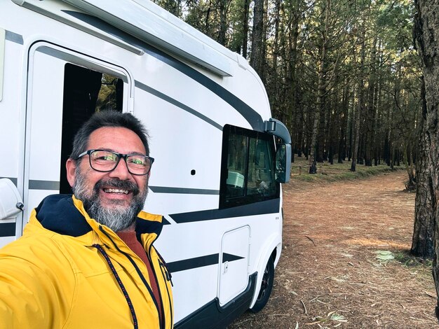 Een volwassen man die een selfie maakt buiten een camper parkert in het natuurpark buiten met bomen Mensen en reizen alternatieve levensstijl vanlife vakantie verhuur van voertuigen Leisure