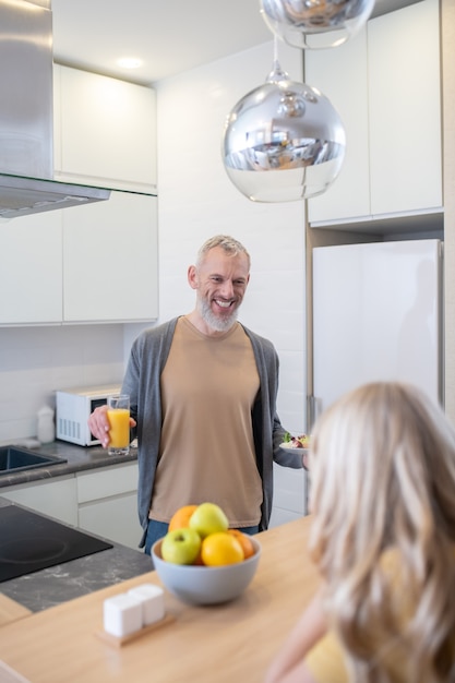 Een volwassen man en zijn dochter praten in de keuken