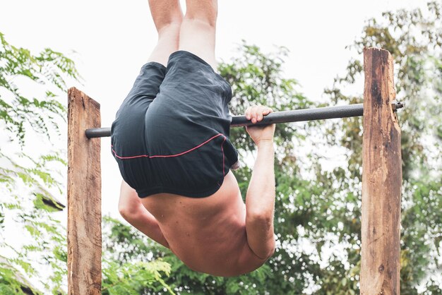 Een volwassen man gaat sporten op een rekstok, maakt salto's en hangt ondersteboven Actieve levensstijl na pensionering