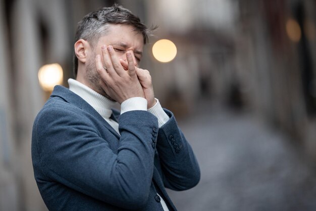 Een volwassen man in een blauw jasje speelt mondharmonica op straat