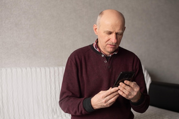 Een volwassen man met een snor en een kaal hoofd probeert de telefoon aan te zetten