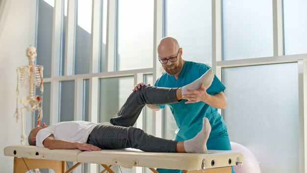 Een volwassen man traint spierkracht met een professionele arts in een moderne revalidatiekliniek...