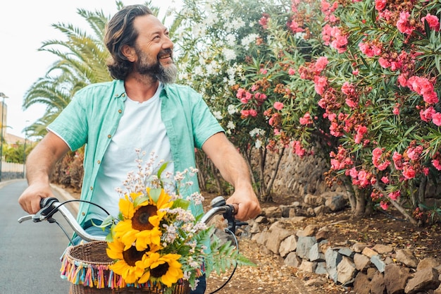 Een volwassen volwassen man geniet van vrijetijdsbesteding buitenshuis, alleen fietsen en lachend uitziende planten en bloemen op straat Gezonde en gelukkige levensstijl mannelijke mensen Groen transportconcept