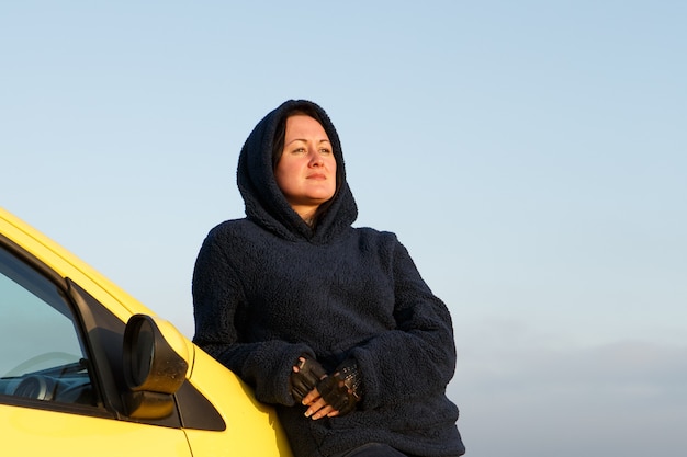 Een volwassen vrouw gekleed in een warme jas reist met de auto door de plaatsen van de natuur vrijheid van denken...