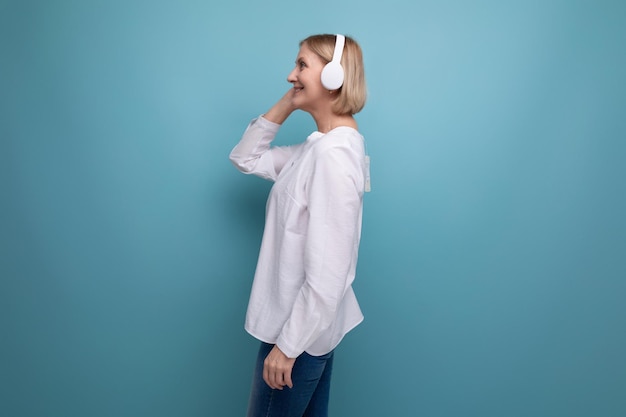 Een volwassen vrouw met een blond kapsel danst naar muziek in draadloze koptelefoon