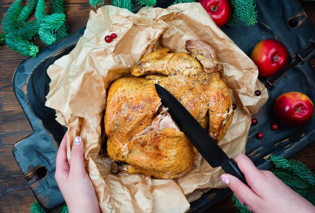 Een voor Thanksgiving gekookte kalkoen ligt op een houten dienblad, appels en takken van nobilis