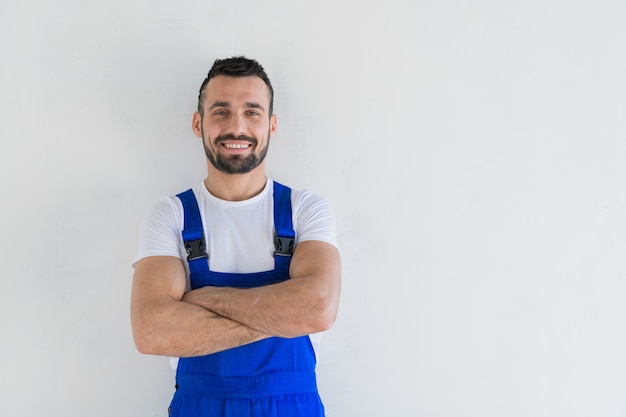 Een voorman staat met gevouwen armen op zijn borst en glimlacht