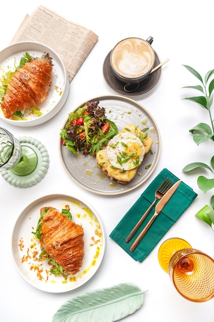 Een voortreffelijke set ontbijtgerechten, croissants, toast, roerei, salade bruschetta op een witte achtergrond