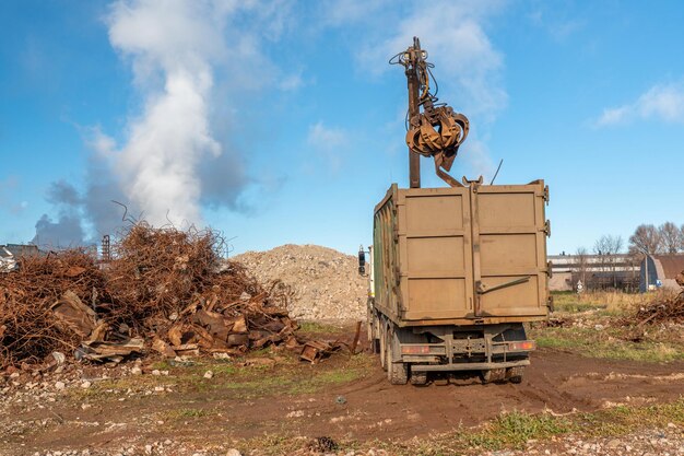 Een vrachtwagen met op de achtergrond een grote stapel hout