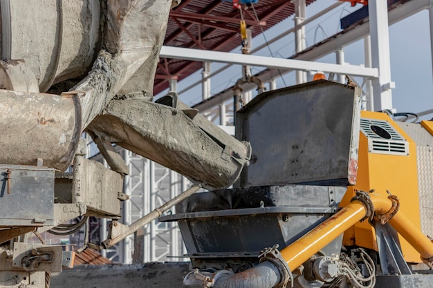 Een vrachtwagen van de betonmixer giet mortel in een betonpomp op een bouwplaats Levering van beton en mortel voor de productie van monolithische gewapende betonwerken Close-up