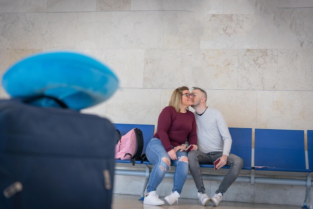 Een vriend geeft zijn vriendin een kus op de wang terwijl ze op het vliegveld wachten om te reizen