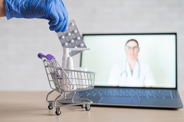 Een vriendelijke arts voert een online consultatie op een laptop Een gehandschoende apotheker stopt medicijnen in een mini-winkelwagentje Het concept van geneeskunde op afstand Bestel medicijnen online