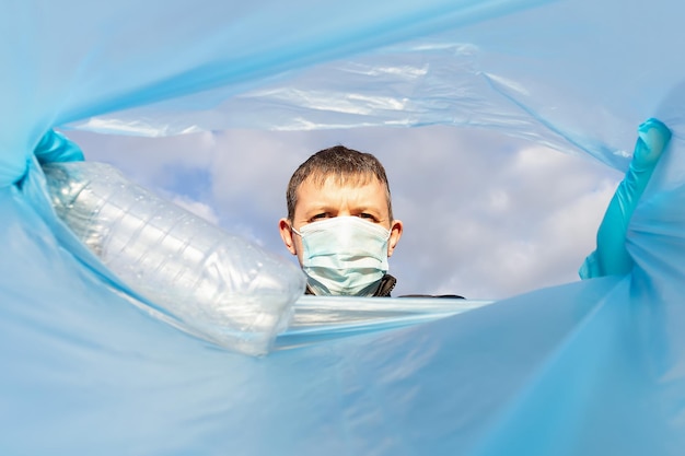 Een vrijwilliger met een beschermend gezichtsmasker gooit een lege fles in een vuilniszak