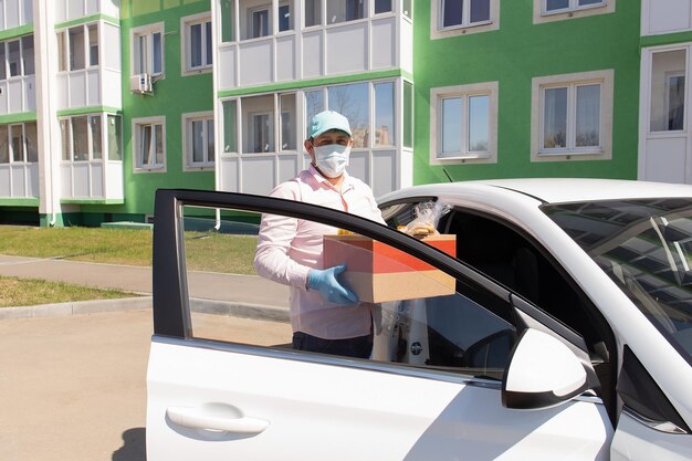 Foto een vrijwilliger staat met een doos boodschappen in zijn handen bij de auto charitatieve donatie bezorging