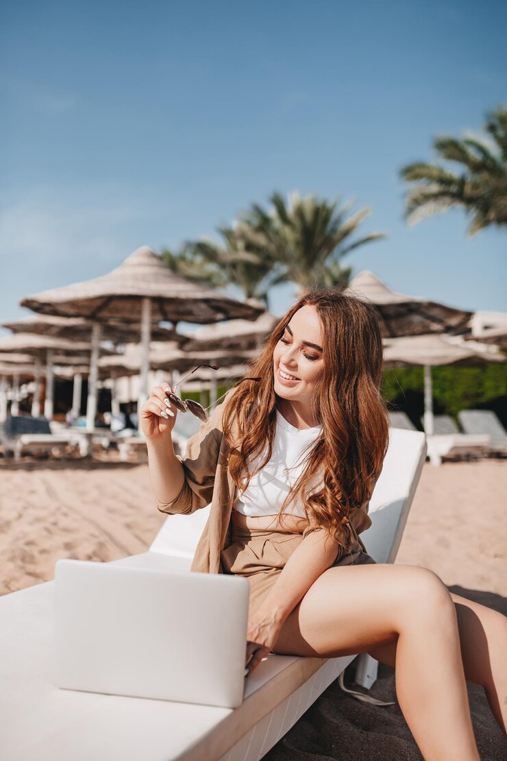 Een vrolijk bloggermeisje werkt op afstand met een laptop op het strand met palmbomen Een vrouw maakt een video van een reis Reist de wereld rond en werkt met sociale netwerken online Modern beroep op afstand