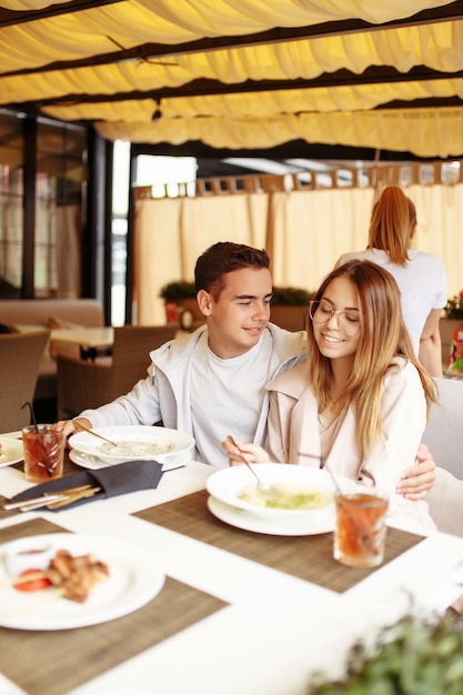 Foto een vrolijk en mooi stel ontspant op een zomerterras in een restaurant met eten en drinken de jongen en het meisje hebben plezier op het terras