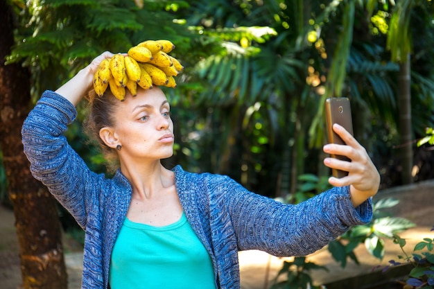 Een vrolijk meisje maakt selfie met bananen op haar hoofd