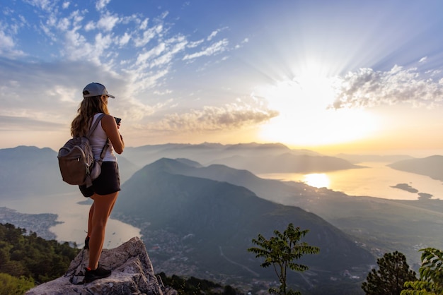 Een vrolijk meisje met een rugzak fotografeert de zeegezichten van montenegro vanaf de top van de berg