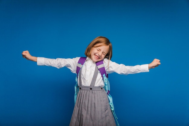 Een vrolijk opgewonden tienermeisje dat haar vuisten balt, is oprecht blij en lacht luid op een blauwe achtergrond Een mooi schoolmeisje lacht Het concept van het geluk van kinderen