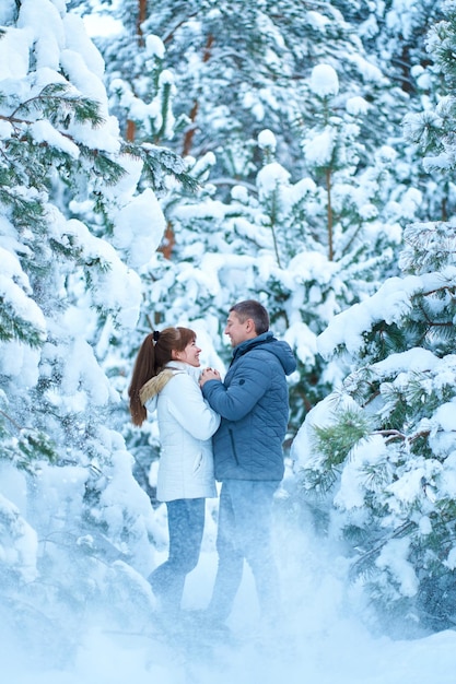 Een vrolijk paar verliefd wandelen in het winterbos zwaar bedekt met sneeuw