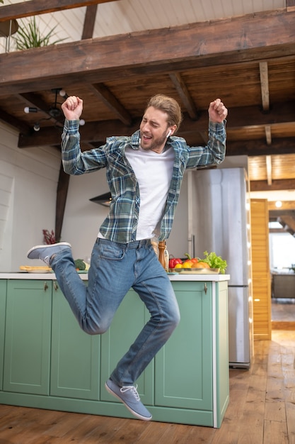 Een vrolijke en energieke man die in zijn keuken springt