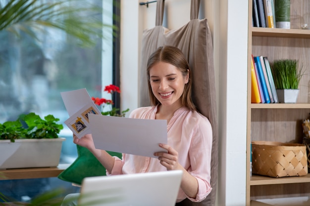 Een vrolijke jonge vrouw die haar creatieve notities bekijkt