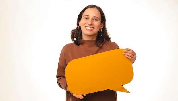 Een vrolijke jonge vrouw die naar de camera lacht, houdt een gele tekstballon vast