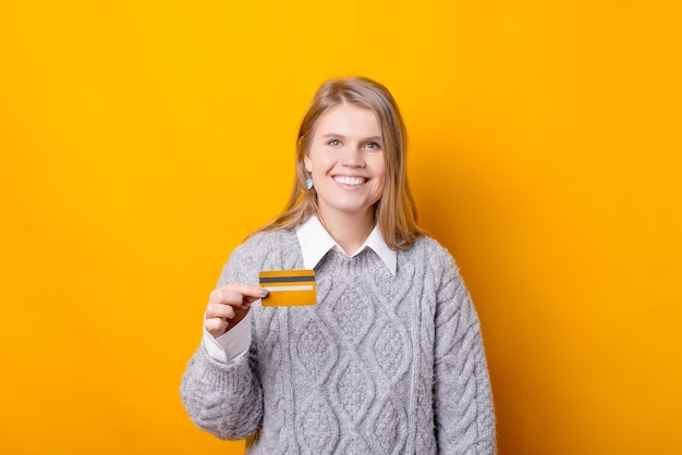 Een vrolijke jonge vrouw houdt een creditcard vast en kijkt lacht