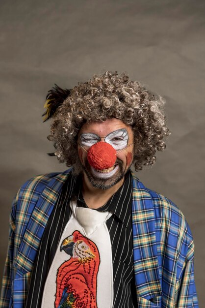 Foto een vrolijke, krullende clown die sluw glimlacht en kijkt naar het portret in close-up.