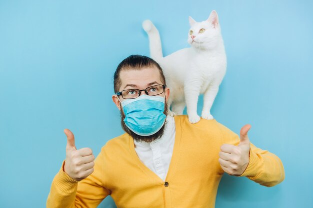 Een vrolijke man in een medisch masker met een witte kat op zijn schouder. pandemie covid 2019. pet.