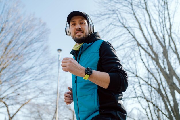Een vrolijke man jogt 's ochtends door het park een atleet met een smartwatch om zijn pols
