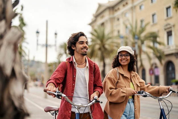 Een vrolijke toerist die een Europese metropool bezoekt terwijl hij fietsen aan de kant duwt