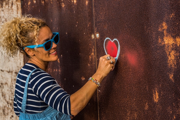 Foto een vrouw alleen op straat die een liefde schildert in een stadsmuur - straatartiest en creatieve verbeelding