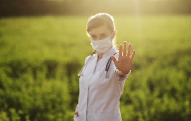 Een vrouw arts in een medisch gezichtsmasker met een einde pandemisch gebaar.