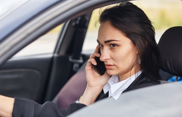 Een vrouw bestuurder met behulp van haar mobiele telefoon tijdens het autorijden