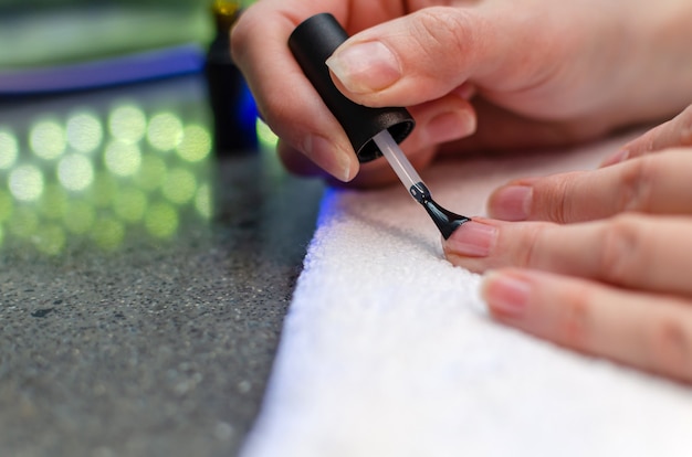 Foto een vrouw brengt een primer aan op haar nagels voordat ze vernis aanbrengt. close-up van een hand.